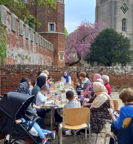 People sitting outside at a table eating a picnic.