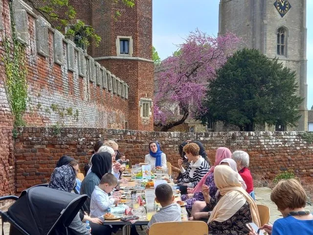 People sitting outside at a table eating a picnic.